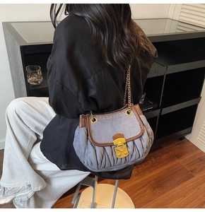 Detail of light blue pleated bucket bag with brown leather trim and gold chain strap