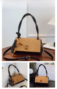 Detail of vintage suede satchel featuring contrast panels, gold twist lock and bead charm
