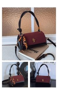 Close-up of burgundy and black leather handbag with knotted handle and ethnic beaded tassel
