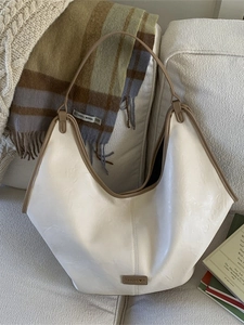 Retro cream tote bag with brown trim and large capacity shown on a soft fabric sofa