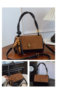 Detail of vintage patchwork handbag with suede finish, gold clasp and bead tassel charm