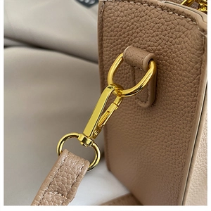 Close-up of luxury brown pebble leather texture and shiny gold metal hardware clips