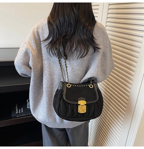 Close-up of black pleated crossbody bag with gold chain strap and vintage metal lock