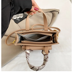 Top view of khaki leather handbag showing large opening with silk scarf on handle