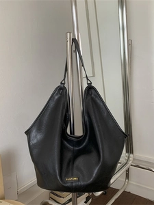 Chic black faux leather tote bag with oily texture and gold logo on a metal hanger