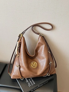 Vintage brown leather tote bag with M metal logo and multiple straps for crossbody use