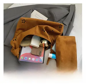 Detail view of large brown suede tote bag with hollow flower design and inner pouch