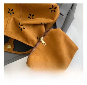 Detail view of brown suede shoulder bag with hollow flower patterns and gold hardware