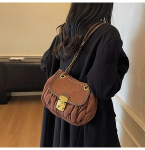 Detail of coffee saddle bag with pleated texture, gold studs and metal chain strap