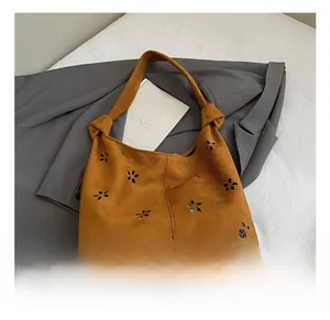 Close-up of brown suede tote bag featuring hollow petal cutouts and knotted handle detail