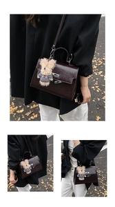 Detail of dark brown vintage Kelly style handbag with a cute plush bear charm accessory