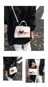 Detailed view of beige minimalist handbag with silver twist lock and plush bear charm