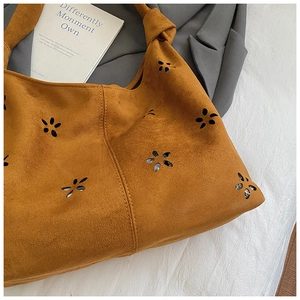 Close-up of ginger suede tote bag featuring floral cutouts and a knotted shoulder strap