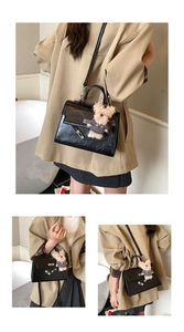 Detail of black textured handbag with metallic twist lock and cute teddy bear charm