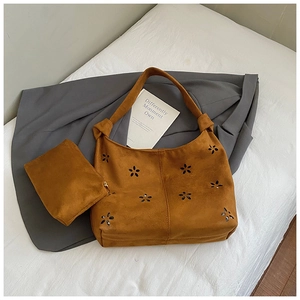 Detail of laser-cut floral pattern on caramel faux suede tote bag with knotted shoulder strap