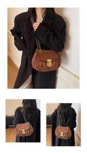 Macro detail of brown pleated suede bag featuring vintage metal lock and gold chain strap