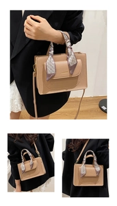 Detail of lychee pattern leather handbag with decorative geometric scarf on the handle