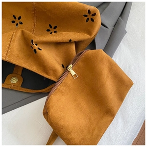 Detail of brown suede tote with laser-cut floral patterns and internal zipper pouch