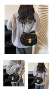 Detail of black pleated shoulder bag with golden buckle and metallic chain strap