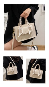Detail of elegant cream handbag featuring silk scarf handle and gold fashion hardware