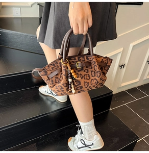 Outdoor shot of vintage leopard print handbag with leather straps and bead charm
