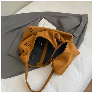 Close-up of vintage brown suede tote bag featuring laser-cut floral patterns and a small pouch