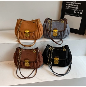 Detailed close-up showing four vintage suede pleated bags with gold metal locks and rivets