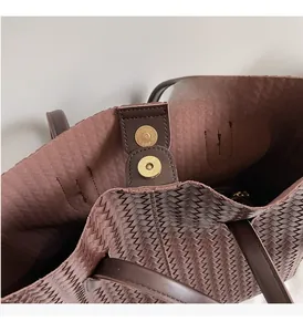 Détail d'un cabas en cuir tressé marron avec fermoir magnétique doré poli élégant