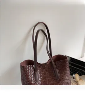 Détail de la poignée du sac cabas tressé marron foncé avec coutures en cuir renforcé
