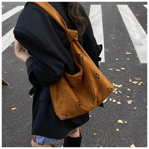 Close-up of caramel laser-cut hollow flower tote bag with knotted shoulder strap detail