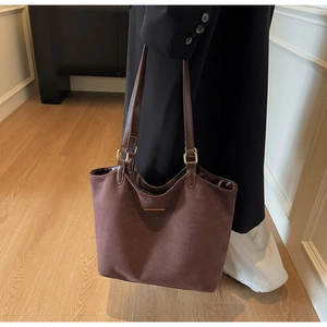 Detail of dark brown matte tote bag with golden metal bar and premium buckle hardware