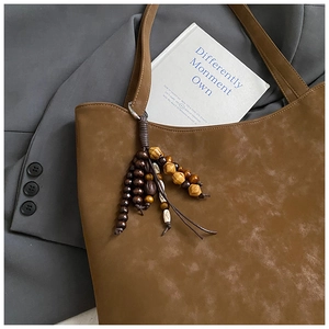 Detail of retro brown suede tote bag featuring a decorative wooden bead tassel pendant