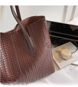 Détail de la texture en cuir tressé marron foncé sur un grand sac cabas pour femme