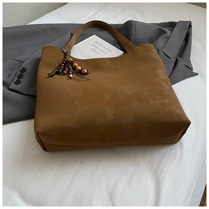 Macro shot of large brown suede tote bag with wooden beads decoration and long handles