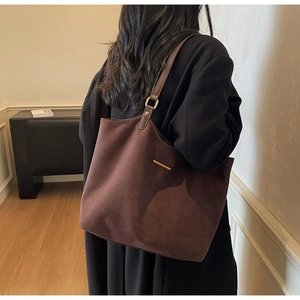 Detail of dark brown matte suede tote bag with gold metal hardware and leather shoulder strap