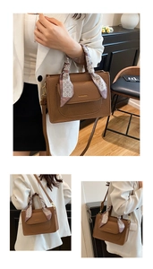 Detail of brown litchi pattern bag featuring a silk scarf wrap and gold fashion logo