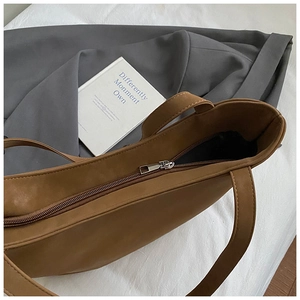 Detail view of the metal zipper closure and spacious interior of the brown leather tote bag