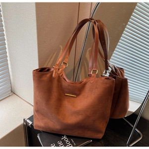 Macro detail of brown suede tote bag featuring a minimalist gold bar metal ornament