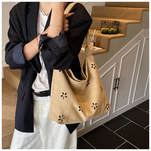 Detail of laser-cut floral pattern and knotted strap on khaki suede hobo bag