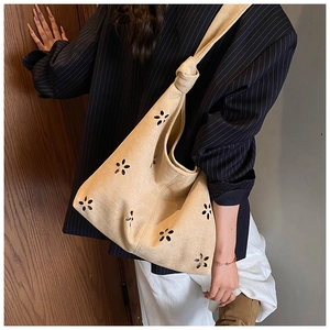 Detail of hollow-out floral pattern on beige suede shoulder bag with knot strap