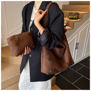 Detail of dark brown suede tote bag featuring laser-cut floral hollow patterns