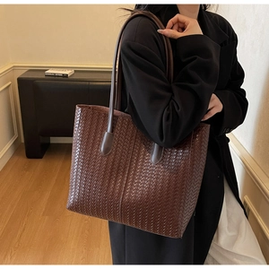 Détail d'un cabas en cuir tressé marron foncé montrant la texture et la grande capacité