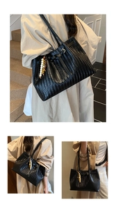 Detailed view of black woven tote bag with V-shaped texture and colorful wooden bead charm