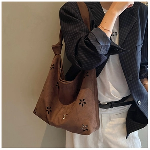 Detail of brown suede shoulder bag with laser-cut floral pattern and knotted strap detail