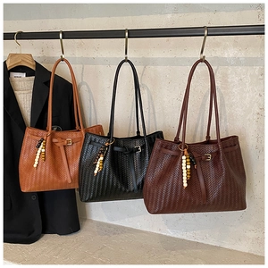 Three minimalist woven tote bags with bead tassels hanging in a stylish display