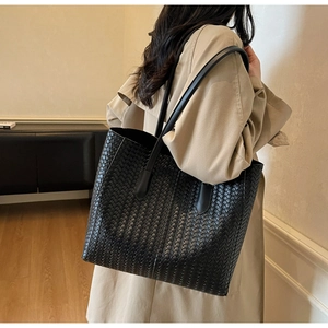 Vue détaillée de la texture tissée du sac fourre-tout noir porté par le mannequin