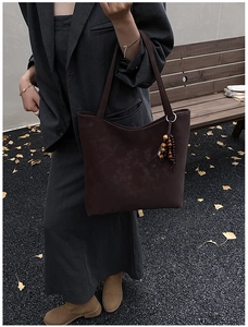 Detail of dark brown faux leather tote bag featuring ethnic style beaded charm ornament