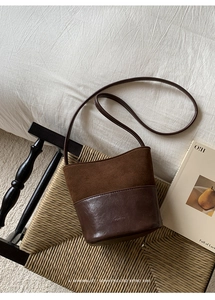 Détail du sac seau rétro en daim marron et cuir avec logo NO FILTER sur une chaise