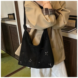 Detailed view of the black laser-cut floral pattern and suede texture on the shoulder bag