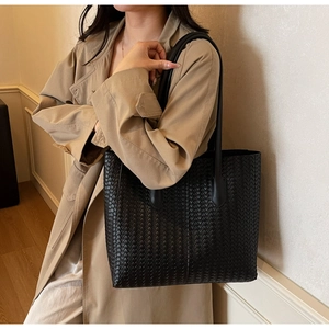 Détail du sac cabas tissé noir à motif damier porté avec un trench-coat beige élégant